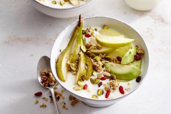 Soy yogurt breakfast with pistachio nuts, apple, pear, lime, avocado and granola.