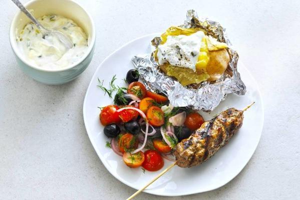 baked potato with Greek skewer and tomato salad